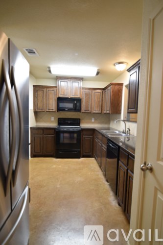 A kitchen with a refrigerator on the left and cabinets above a counter.