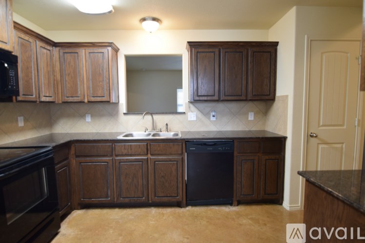 A kitchen with brown cabinets and a black dishwasher.