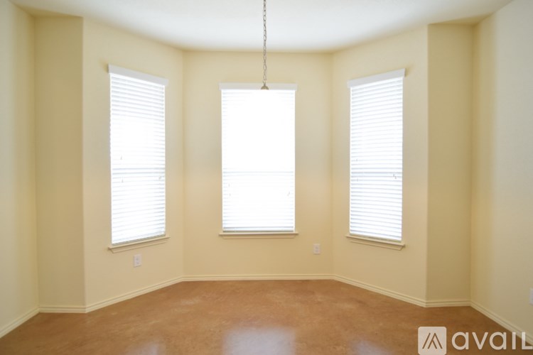 A room with a brown floor and three windows.