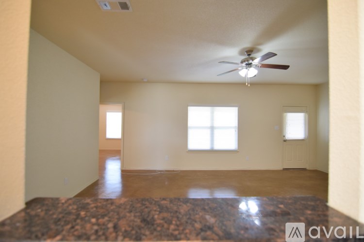 A spacious room with a ceiling fan and two windows.