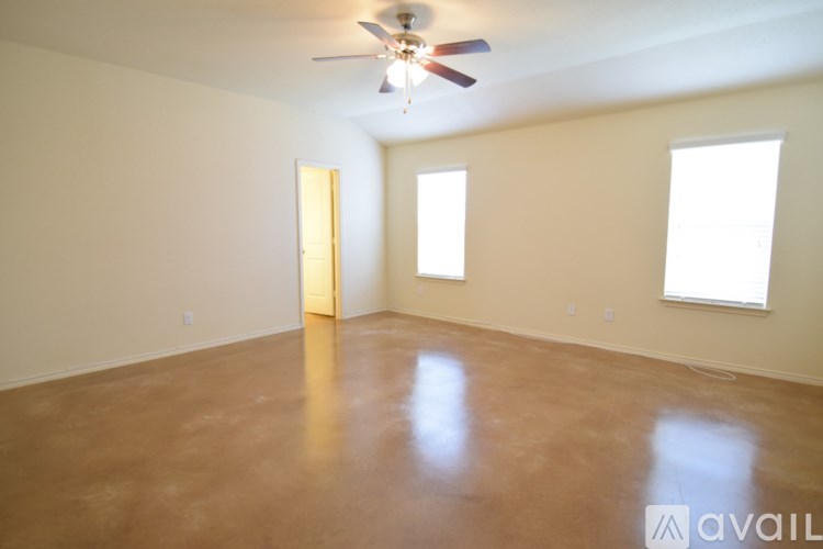 Empty room with a ceiling fan and two windows.
