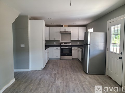 A kitchen with white cabinets and a grey refrigerator.