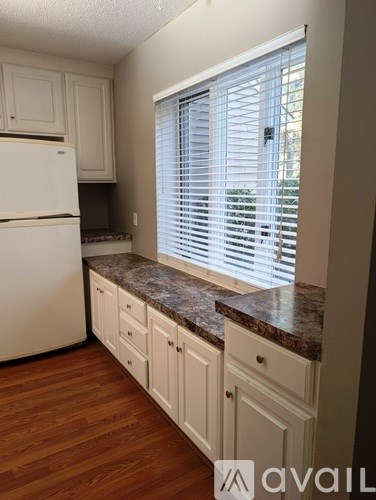 A kitchen with a white refrigerator and cabinets.