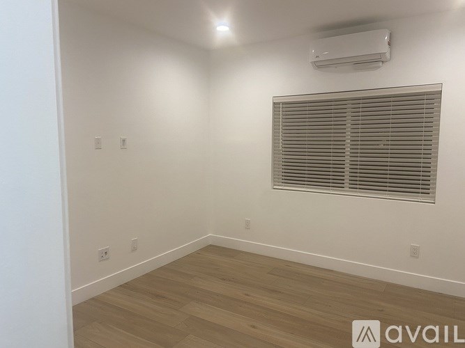 A room with a window covered by blinds and a wall-mounted air conditioner.