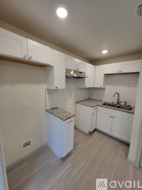 A kitchen with white cabinets and a granite countertop.