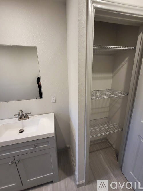 A bathroom with a sink, mirror, and empty shelves.
