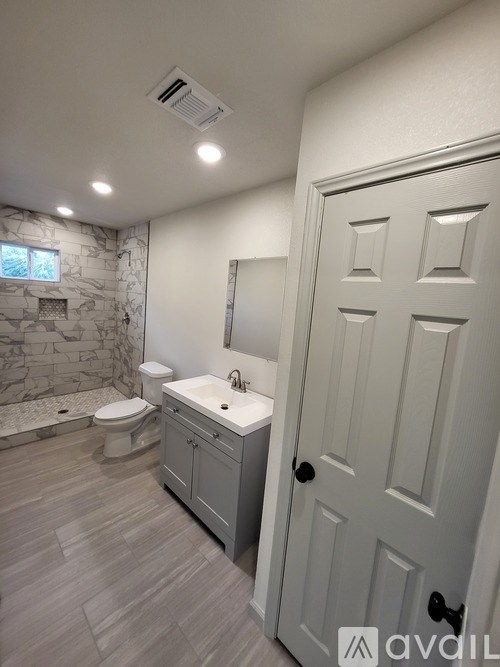 A bathroom with a toilet, sink, and a stone wall.