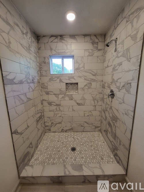 A bathroom with a marble tile shower and a window.