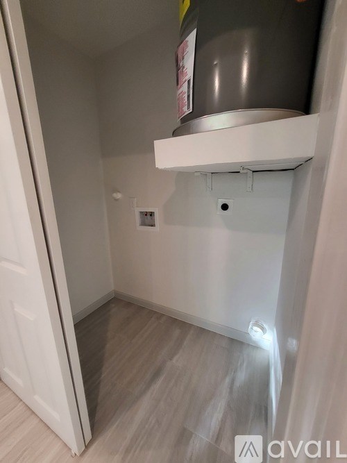 A small, empty room with a white door and a grey floor.