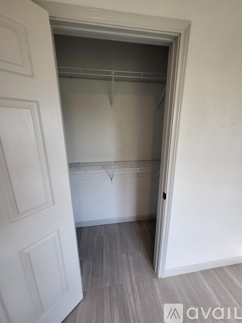 A white door is open to a room with a grey floor and a white wall.