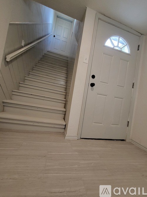 A white door with a window above it is on the right side of a staircase.