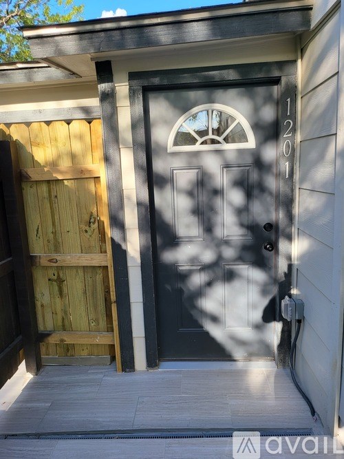 A black door with a glass window above it and a wooden door to the left.