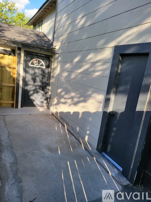 A black door with a white logo is on a grey building.