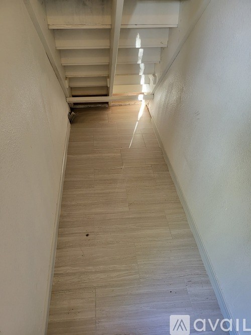 A long hallway with wooden floors and white walls.