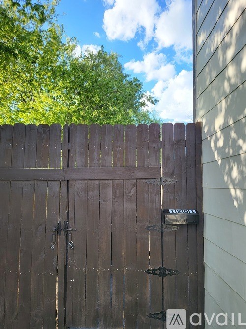 A brown wooden gate with a black handle and a lock.