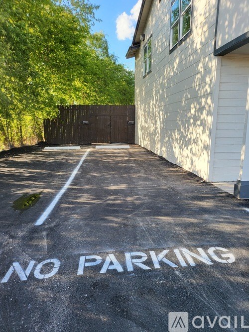 A white house with a "NO PARKING" sign painted on the pavement in front of it.