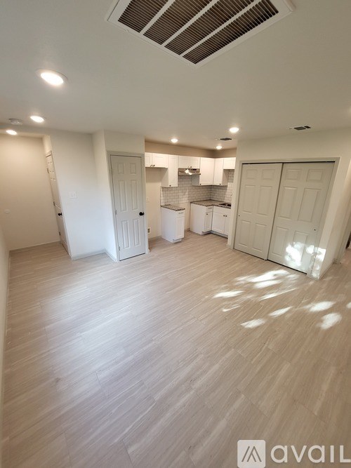 A spacious room with wooden flooring and white walls.