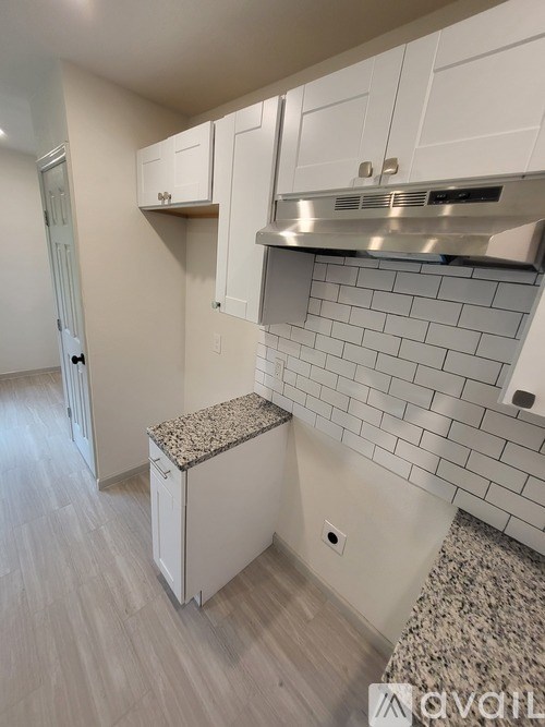 A kitchen with white cabinets and a granite countertop.