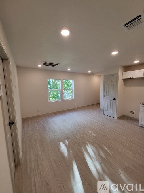 A spacious room with wooden flooring and a window.