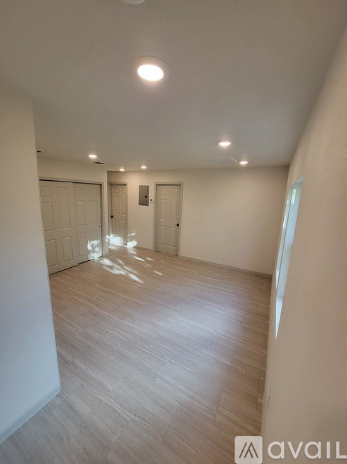 A spacious room with wooden flooring and white walls.