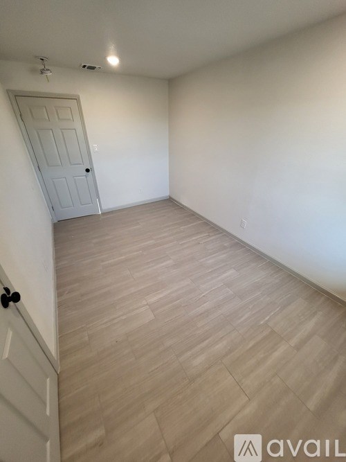 A room with a white door and wooden flooring.