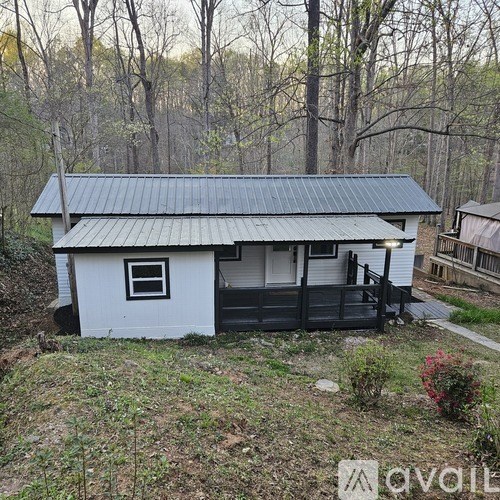 A small white house with a black roof and a porch.