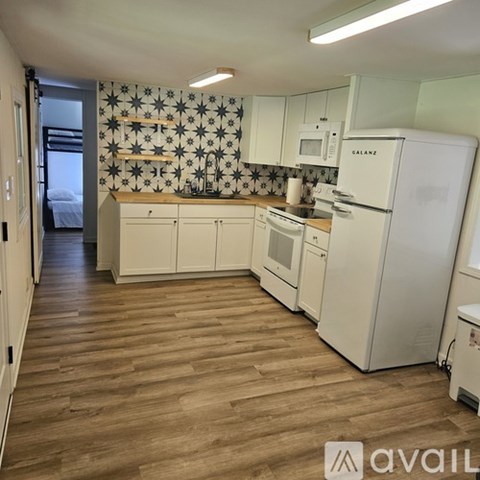 A kitchen with white appliances and wooden floors.