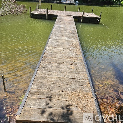 A wooden dock extends into a greenish body of water.