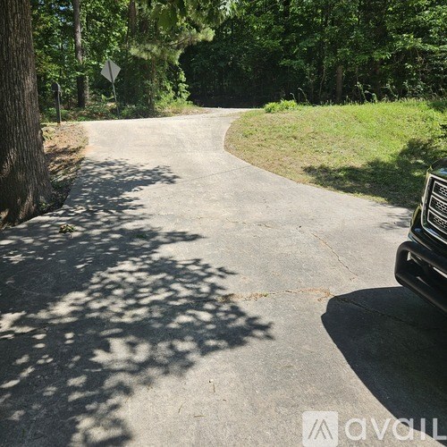 A car is parked on the side of a curvy road in a wooded area.