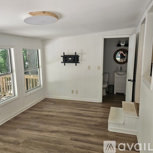 A room with a wooden floor and a flat screen TV mounted on the wall.