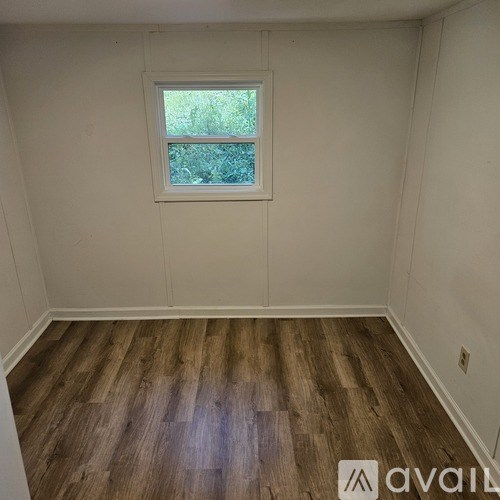 A room with wooden flooring and a window.