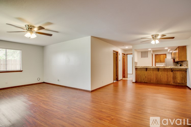 A room with wooden floors and two ceiling fans.