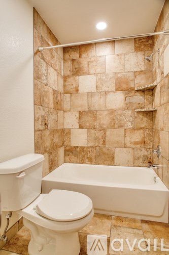 A bathroom with a toilet, tub and tiled walls.