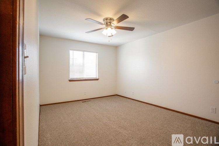 A room with a ceiling fan and a window with blinds.