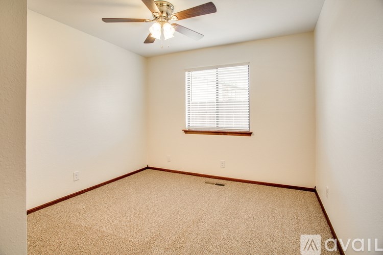 A room with a ceiling fan and a window with blinds.