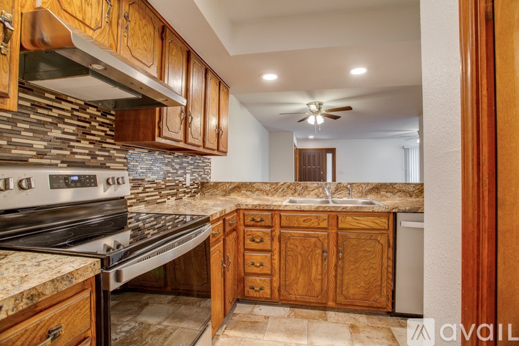 A kitchen with wooden cabinets and a stone backsplash.