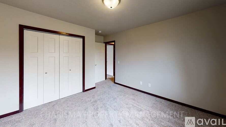 A room with a carpeted floor and a white wall with a door on the left side.