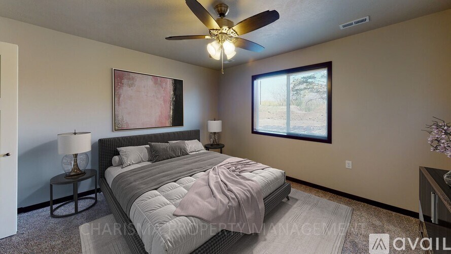 A bedroom with a bed, a ceiling fan, and a window.