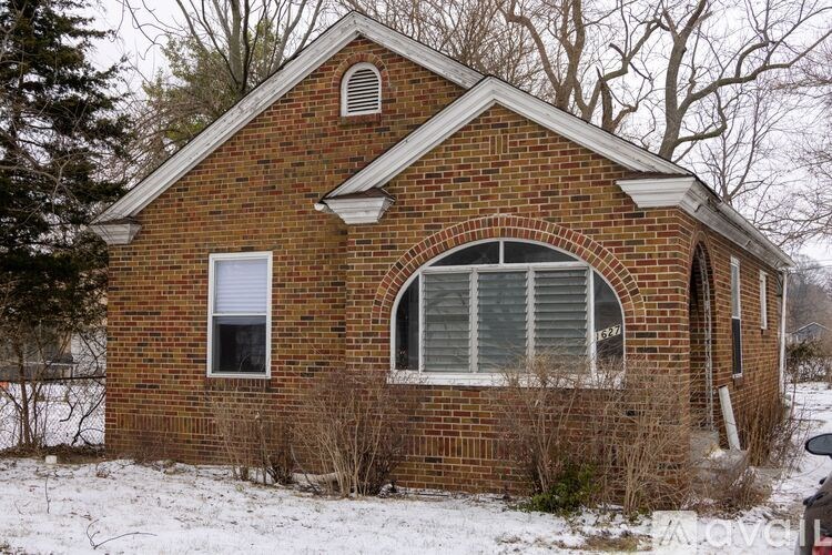 A small brick house with a white window and a small arched window.