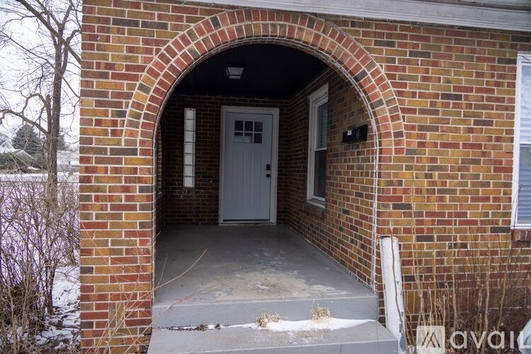 A brick archway leads to a white door.