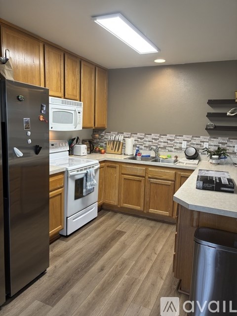 A kitchen with wooden cabinets and a stainless steel refrigerator.