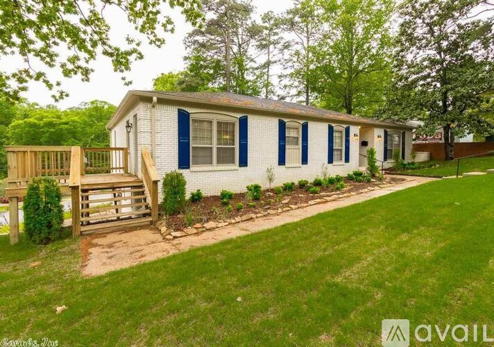 A white house with blue shutters and a wooden deck.