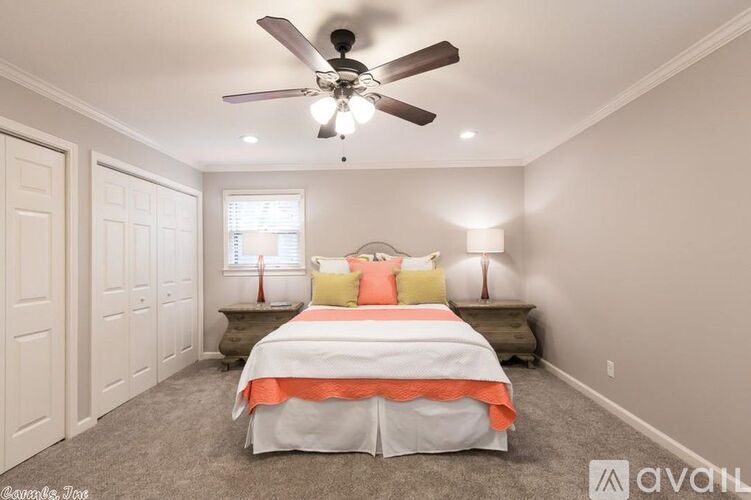 A bedroom with a bed, nightstands, and a ceiling fan.