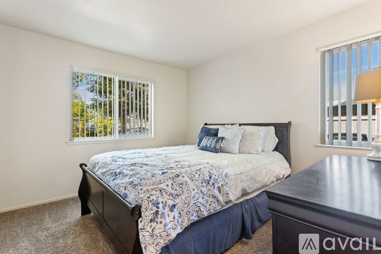 A bedroom with a bed, nightstand, and window with blinds.