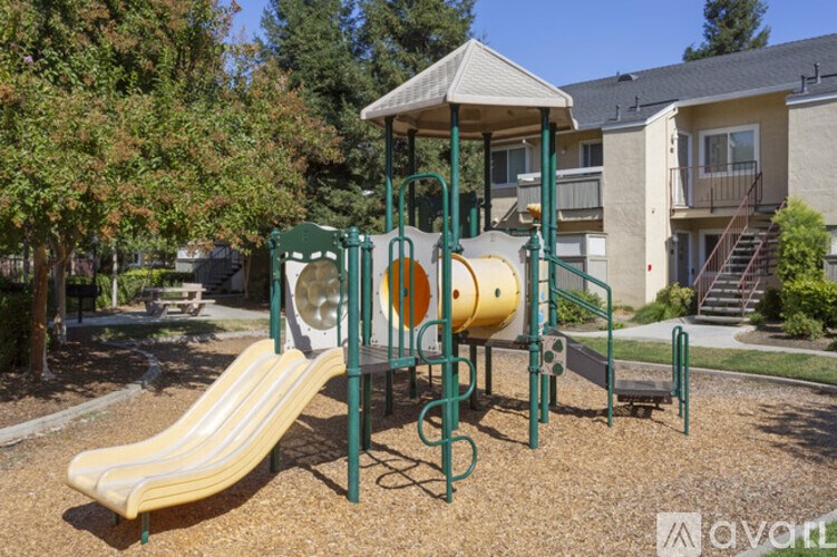 A playground with a yellow slide and a green canopy.