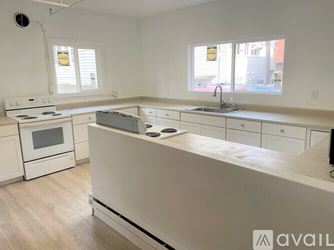 A kitchen with white appliances and cabinets is available for rent.