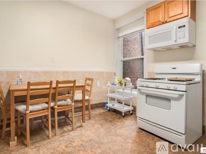 A kitchen with a white stove, wooden chairs, and a table.