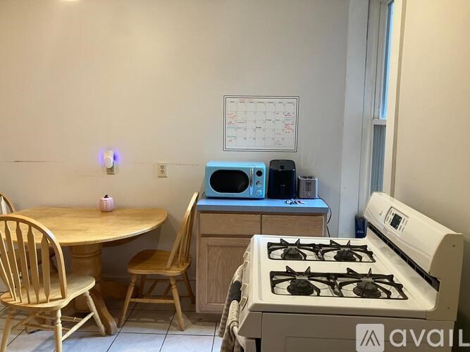 A kitchen with a table, chairs, a stove, and a microwave.
