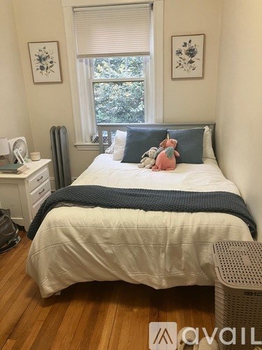 A bedroom with a bed, nightstand, and window.
