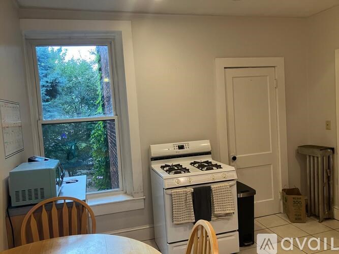 A small room with a window, a stove, and a chair.
